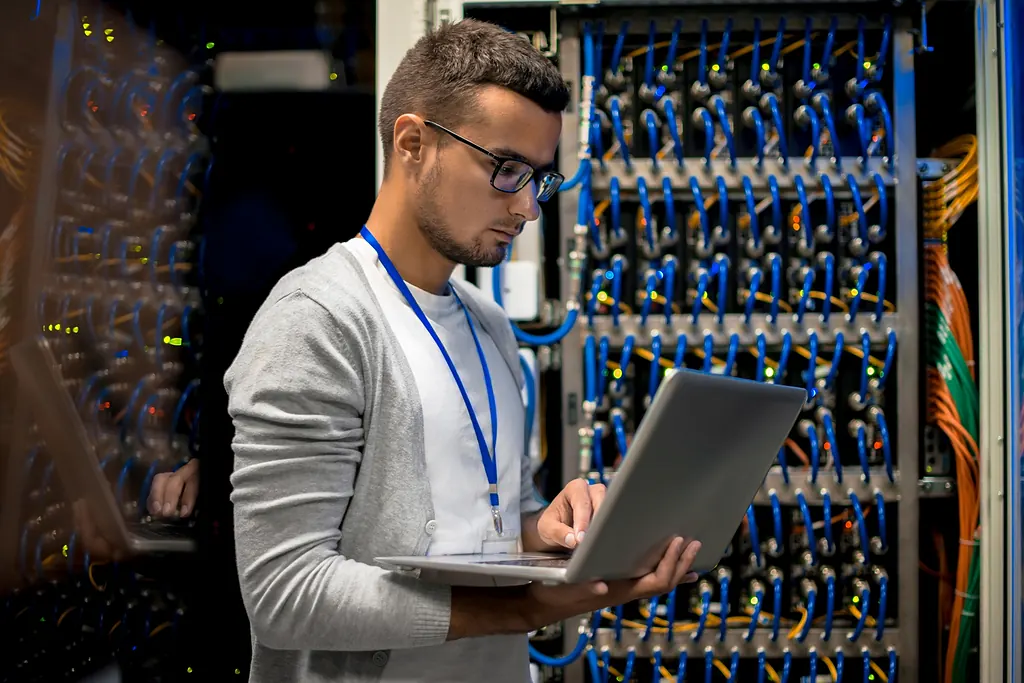 IT-Fachkraft mit Laptop im Serverraum